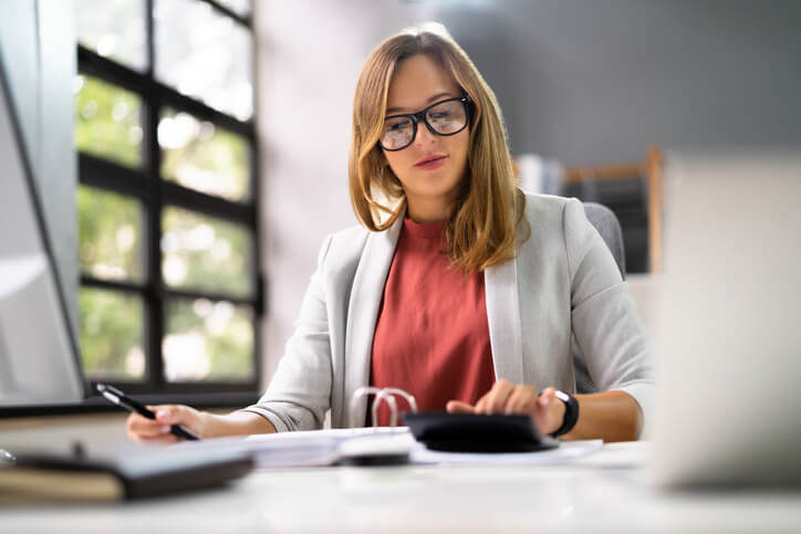A payroll administrator training graduate calculating employee pay and deductions